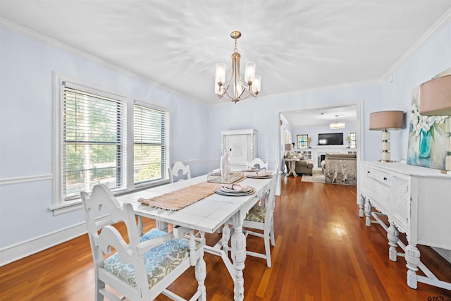 dining space featuring dark wood-type flooring, crown molding, and a notable chandelier