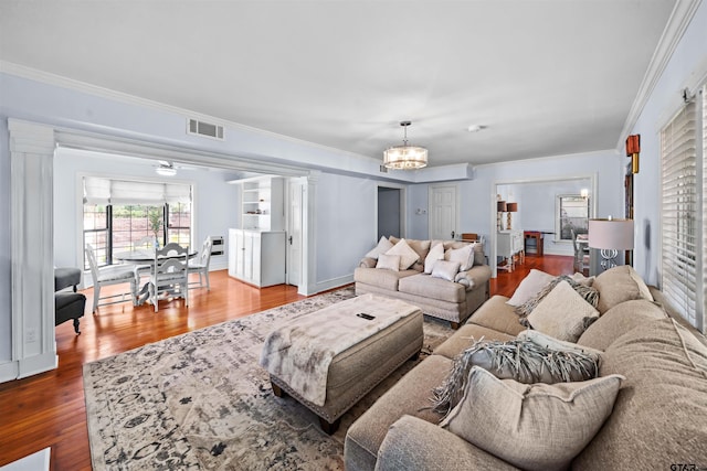 living room featuring ornamental molding, hardwood / wood-style flooring, decorative columns, and an inviting chandelier