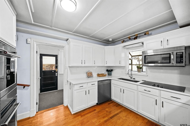 kitchen with stainless steel appliances, white cabinetry, sink, and light wood-type flooring