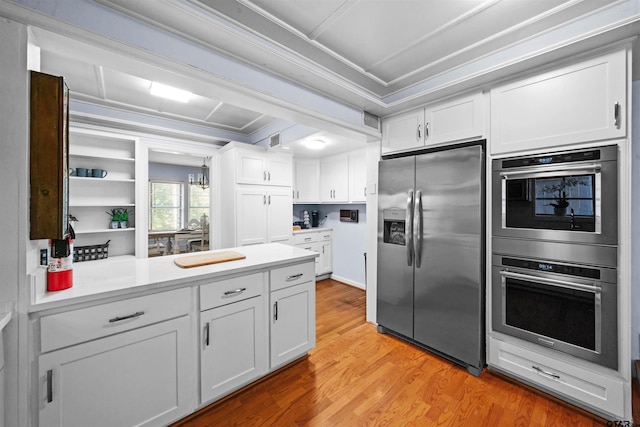 kitchen featuring crown molding, light wood-type flooring, appliances with stainless steel finishes, a notable chandelier, and white cabinets