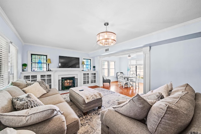 145 Rowland Pl, Tyler, TX 75701 - living room featuring a chandelier, ornamental molding, a fireplace with flush hearth, wood finished floors, and decorative columns