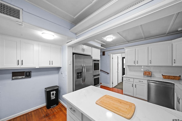 kitchen with dark wood-type flooring, white cabinetry, decorative backsplash, and appliances with stainless steel finishes