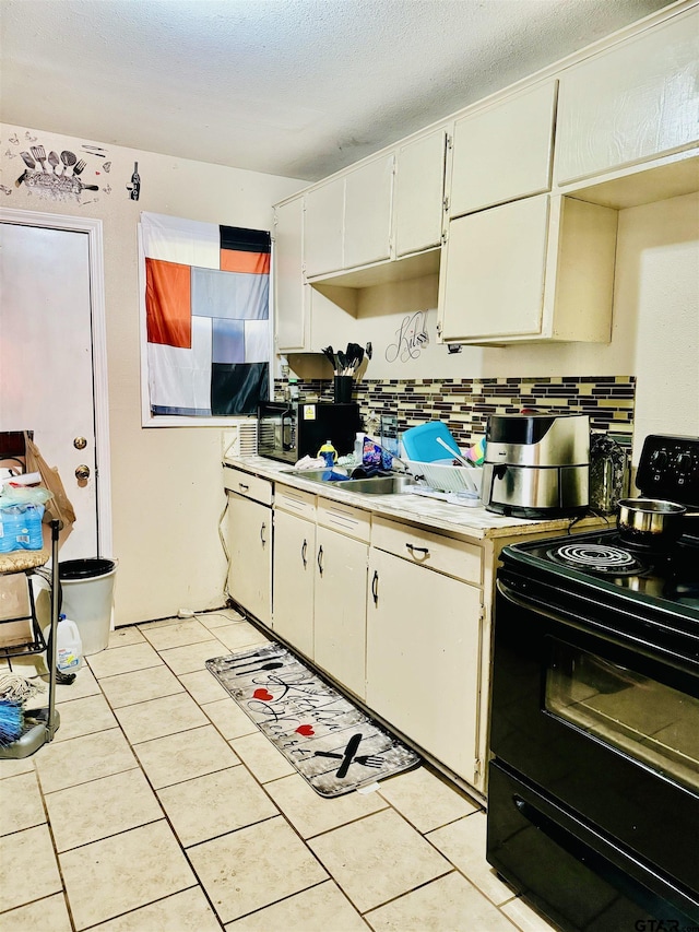 kitchen featuring tasteful backsplash, white cabinets, light tile patterned flooring, and black appliances