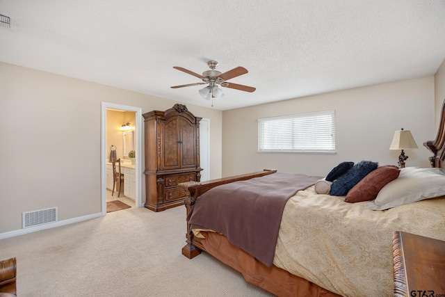 bedroom featuring a textured ceiling, baseboards, ensuite bath, light colored carpet, and visible vents