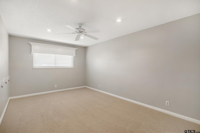 empty room with light carpet, baseboards, a textured ceiling, and a ceiling fan
