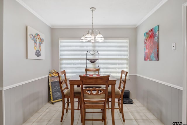dining area with wainscoting, ornamental molding, light tile patterned floors, and a chandelier