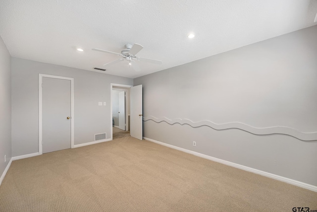 spare room with a ceiling fan, baseboards, light colored carpet, and visible vents