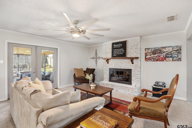 living room featuring crown molding, french doors, visible vents, a ceiling fan, and a fireplace