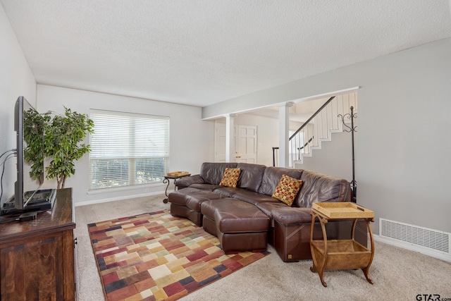 living room featuring carpet flooring, a textured ceiling, baseboards, and visible vents