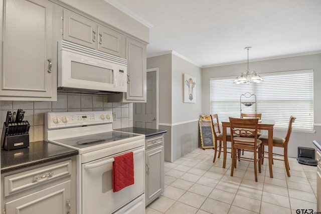 kitchen featuring crown molding, white appliances, dark countertops, an inviting chandelier, and backsplash