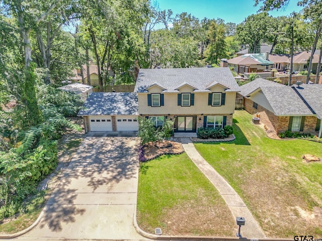 colonial house with roof with shingles, driveway, a front lawn, brick siding, and a garage