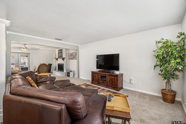living room with a textured ceiling, carpet, baseboards, ceiling fan, and a fireplace