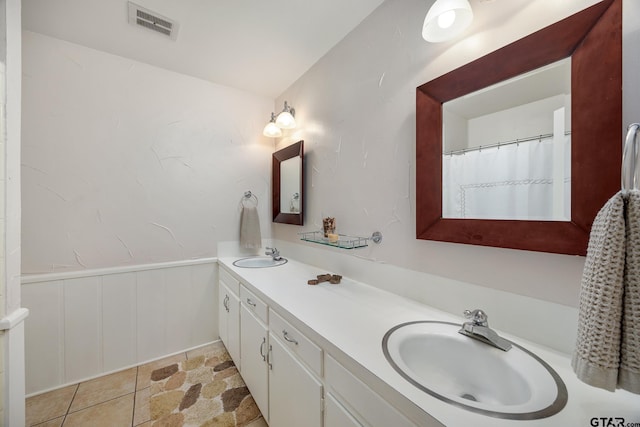 full bath featuring double vanity, wainscoting, visible vents, and a sink