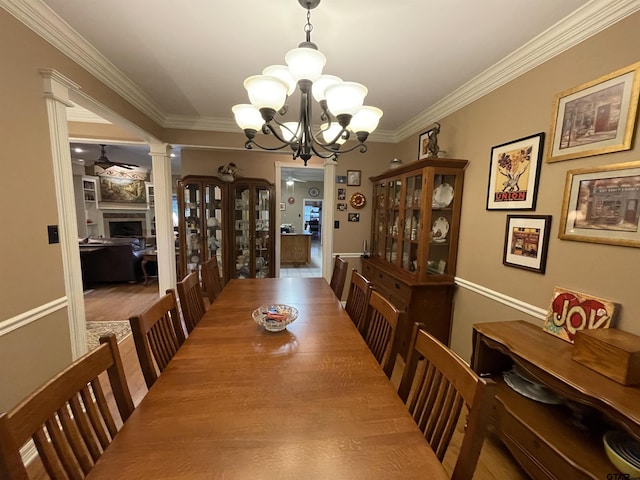 3617 Flagstone Dr, Tyler, TX 75707 - dining area featuring a chandelier, crown molding, ornate columns, a fireplace, and wood finished floors