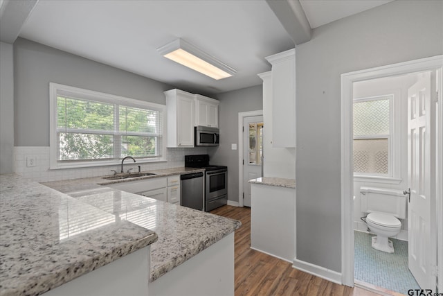 513 E Young, Longview, TX 75602 - kitchen with stainless steel appliances, white cabinets, wood finished floors, decorative backsplash, and light stone counters