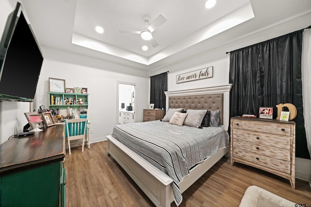 bedroom with a tray ceiling, baseboards, recessed lighting, and wood finished floors