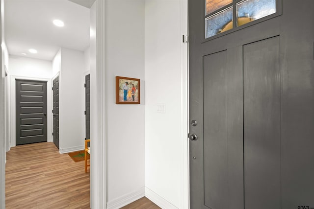 foyer entrance featuring baseboards, wood finished floors, and recessed lighting