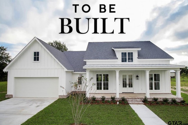 view of front of property featuring french doors, a front lawn, covered porch, and a garage