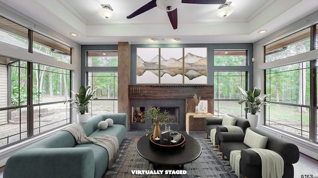 sunroom / solarium with a raised ceiling, a tile fireplace, ceiling fan, and plenty of natural light