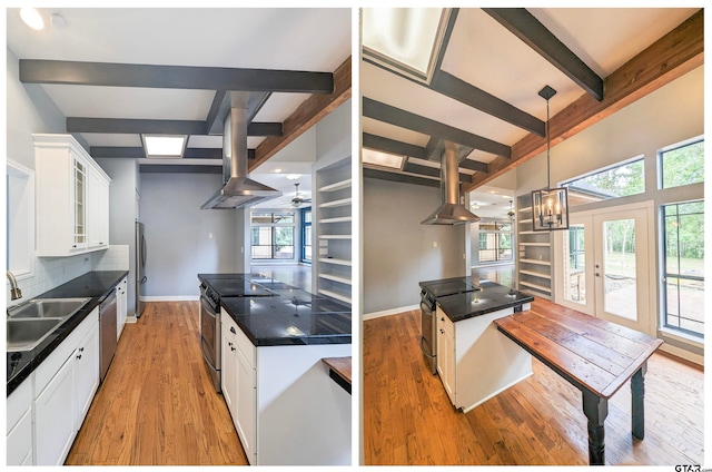 kitchen featuring pendant lighting, white cabinets, wall chimney range hood, sink, and appliances with stainless steel finishes