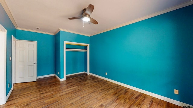 unfurnished bedroom featuring ceiling fan, wood-type flooring, ornamental molding, and a closet