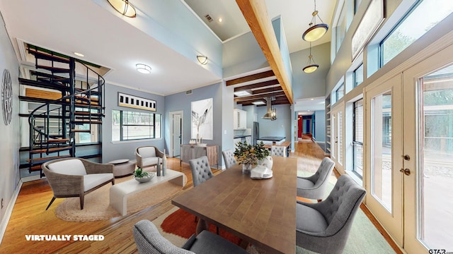 dining area with french doors, crown molding, light wood-type flooring, a towering ceiling, and beamed ceiling