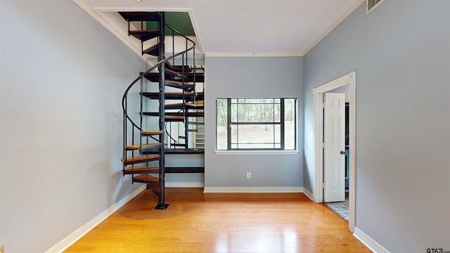 staircase with hardwood / wood-style floors and crown molding