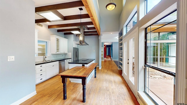 kitchen featuring white cabinets, appliances with stainless steel finishes, light wood-type flooring, and decorative light fixtures