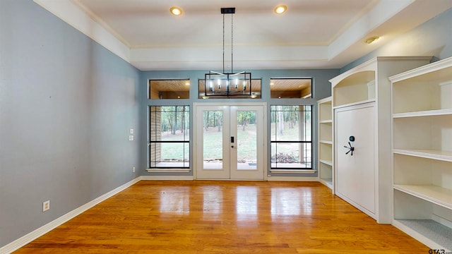 entryway featuring french doors, light hardwood / wood-style flooring, ornamental molding, and a notable chandelier