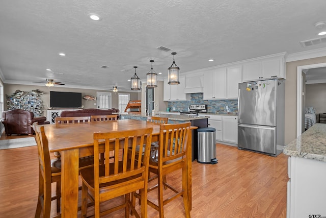 kitchen featuring light stone counters, stainless steel appliances, ceiling fan, pendant lighting, and white cabinets