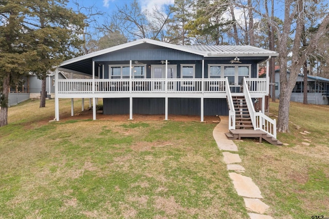 view of front of property with ceiling fan, a deck, and a front lawn