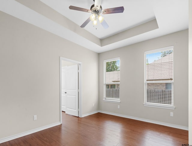 unfurnished room featuring dark hardwood / wood-style flooring, ceiling fan, and a tray ceiling