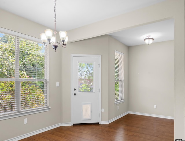 entryway featuring dark wood-type flooring, a healthy amount of sunlight, and an inviting chandelier