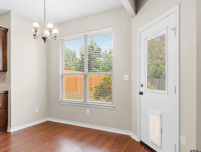 unfurnished dining area with a chandelier, a wealth of natural light, and hardwood / wood-style flooring