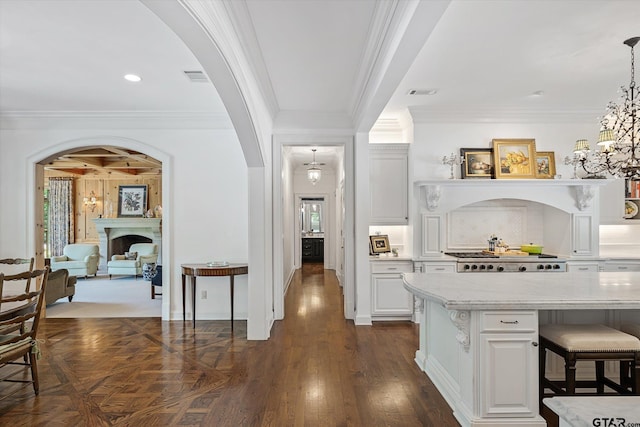 kitchen with ornamental molding, white cabinetry, a kitchen bar, dark hardwood / wood-style flooring, and pendant lighting