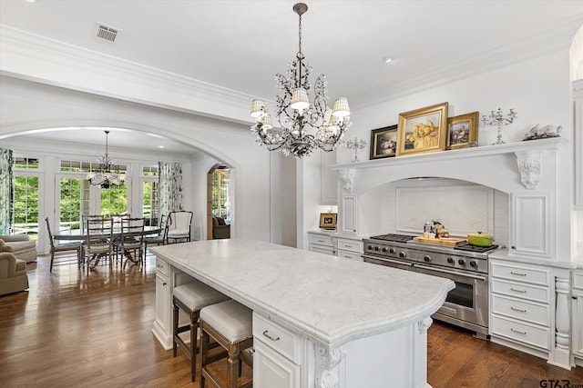 kitchen featuring high end stainless steel range oven, a center island, dark hardwood / wood-style floors, crown molding, and white cabinetry