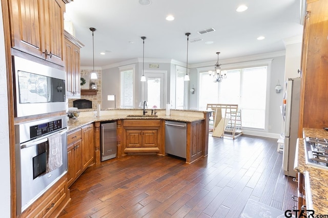 521 Susie St, Chandler, TX 75758 - kitchen with stainless steel appliances, a sink, a peninsula, ornamental molding, and dark wood-type flooring