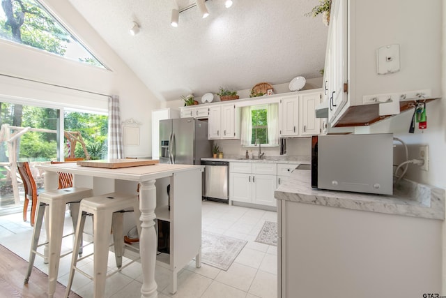 506 S King Lake Rd, Scroggins, TX 75480 - kitchen with appliances with stainless steel finishes, white cabinets, range hood, light tile patterned floors, and a kitchen bar