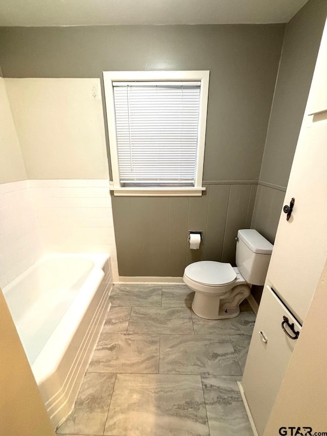 2009 Lindbergh Rd, Tyler, TX 75703 - bathroom with a garden tub, a wainscoted wall, and marble look tile flooring