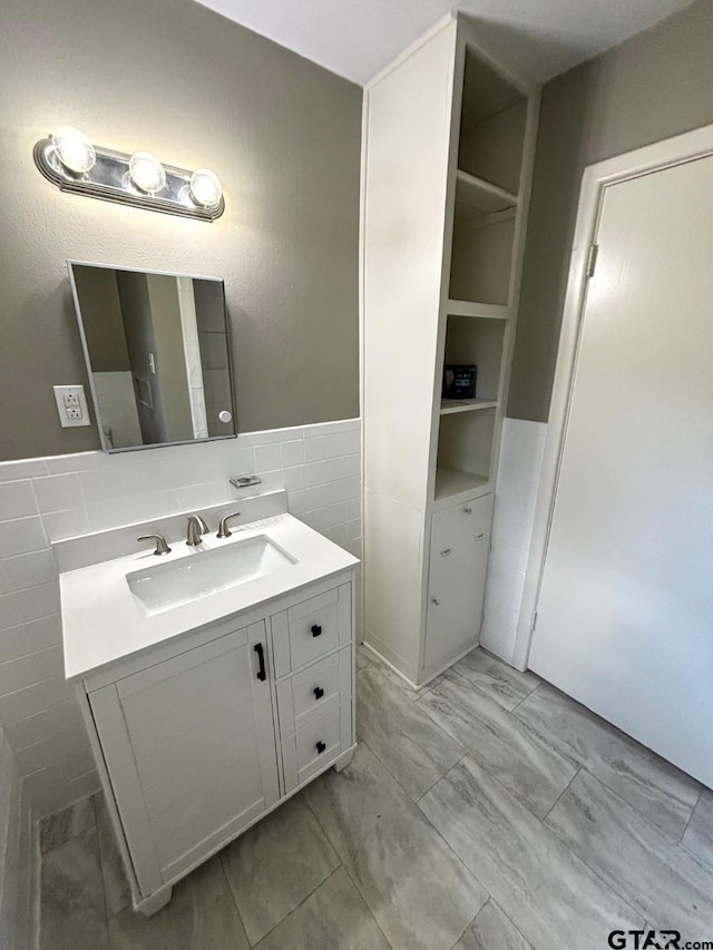 2009 Lindbergh Rd, Tyler, TX 75703 - bathroom featuring vanity, marble finish floors, tile walls, and wainscoting