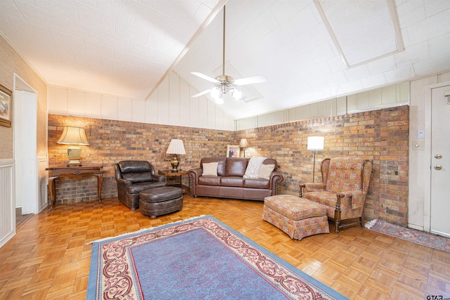 living room featuring high vaulted ceiling, light parquet flooring, ceiling fan, and brick wall