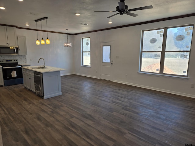 kitchen with sink, white cabinetry, hanging light fixtures, appliances with stainless steel finishes, and a kitchen island with sink