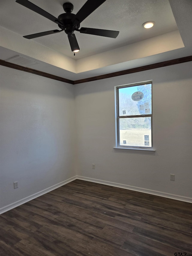 spare room with ceiling fan, dark hardwood / wood-style flooring, a raised ceiling, and a textured ceiling