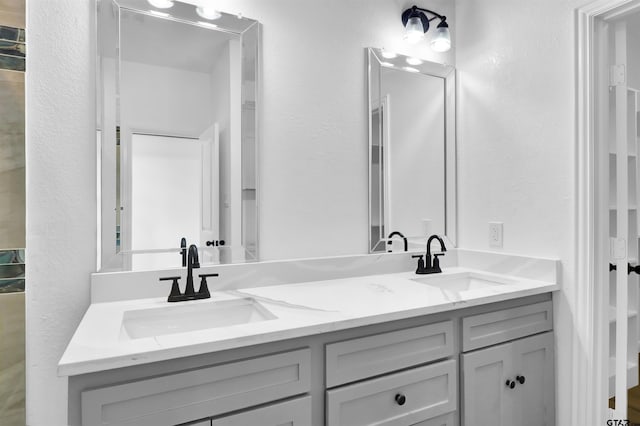 bathroom with a textured wall, a sink, and double vanity