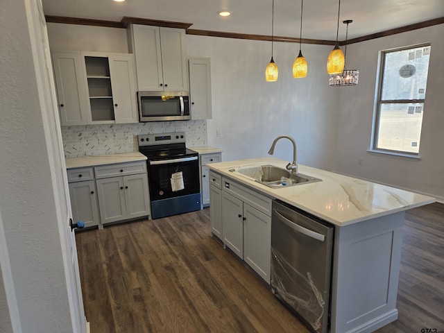 kitchen featuring appliances with stainless steel finishes, decorative light fixtures, sink, a kitchen island with sink, and light stone countertops