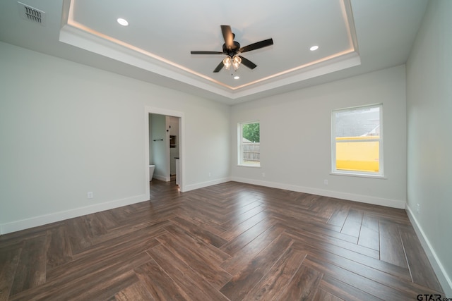 unfurnished room with ceiling fan, a raised ceiling, and dark parquet floors