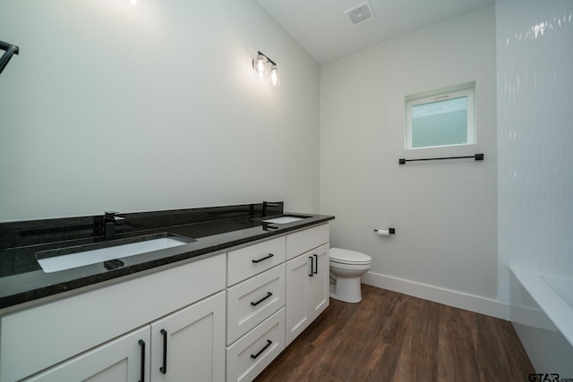 bathroom featuring hardwood / wood-style floors, a washtub, vanity, and toilet