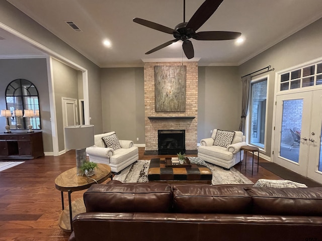 living room featuring french doors, crown molding, a brick fireplace, dark hardwood / wood-style floors, and ceiling fan