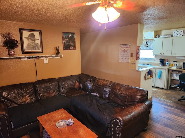 living room featuring ceiling fan, dark hardwood / wood-style flooring, and a textured ceiling