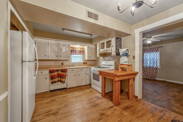 kitchen with white cabinetry, sink, white appliances, and light hardwood / wood-style floors